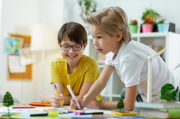 État de l'environnement. Rire de beaux garçons passant du temps en classe et créant un travail créatif