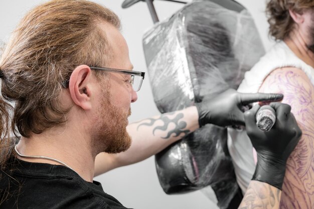 Tatouage de salon Gros plan d'un tatoueur travaillant Tatoueur tatouant au studio Photographie de haute qualité