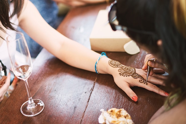 Photo tatoueur au henné indien dessinant l'art de ligne unique sur la main des femmes