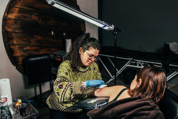 Un tatoueur fait un tatouage dans un salon