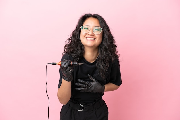 Tatoueur femme asiatique isolée sur fond rose souriant beaucoup