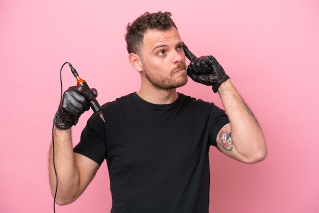 Tatoueur homme brésilien isolé sur fond rose ayant des doutes et pensant