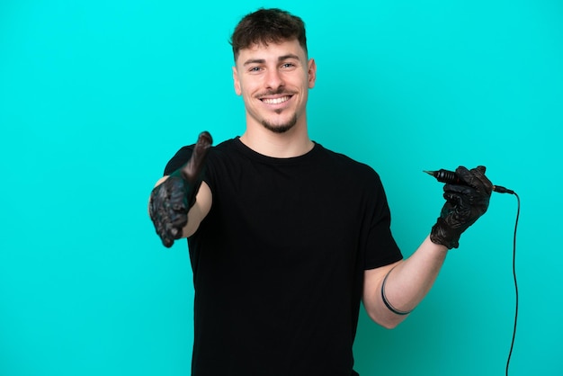 Tatoueur homme caucasien isolé sur fond bleu se serrant la main pour conclure une bonne affaire