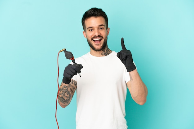 Tatoueur homme sur fond bleu isolé pointant vers une excellente idée