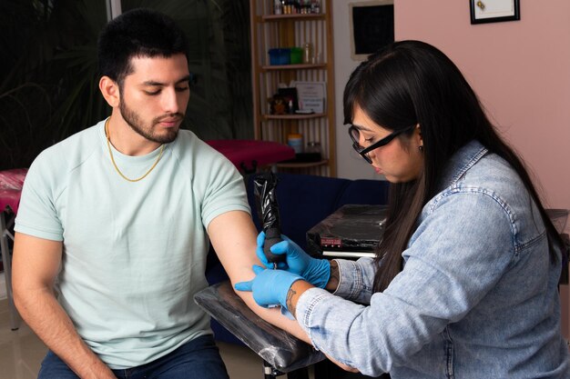 Tatoueur de jeune femme pendant le travail dans un studio