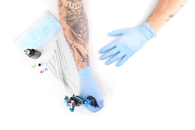 Tatoueur mains dans des gants bleus avec un équipement spécial isolé sur fond blanc gros plan