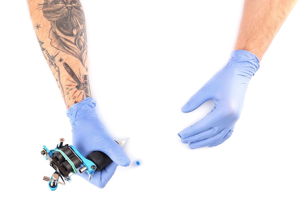 Photo tatoueur mains dans des gants bleus avec machine à tatouer isolé sur fond blanc gros plan