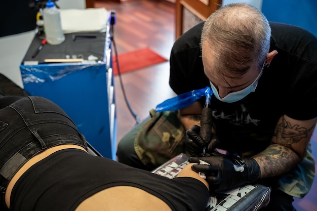 Tatoueur méconnaissable faisant un tatouage sur le bras d39une femme concept de travail et de concentration