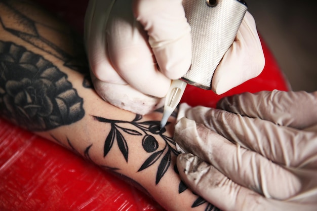 Tatoueur professionnel faisant le tatouage sur la main du client