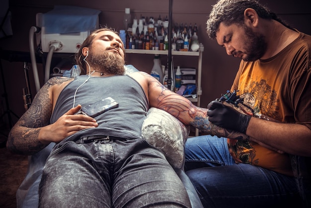 Un tatoueur professionnel fait des photos de tatouage dans un studio de tatouage./Le maître travaille dans un studio de tatouage.