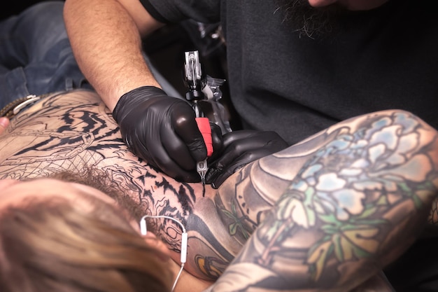 Photo un tatoueur professionnel fait un tatouage dans le salon du client