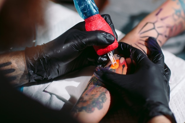 Un tatoueur professionnel fait un tatouage sur la main d'une jeune fille.