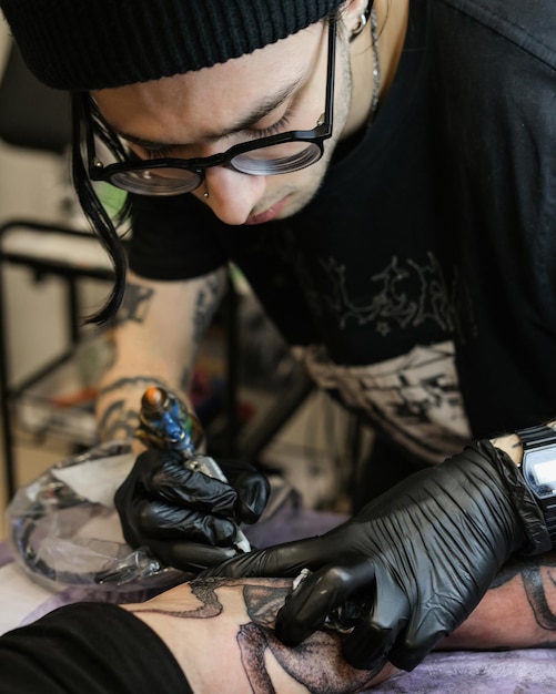 Tatoueur professionnel fourre un tatouage sur la main de l'homme Tatoueur au travail