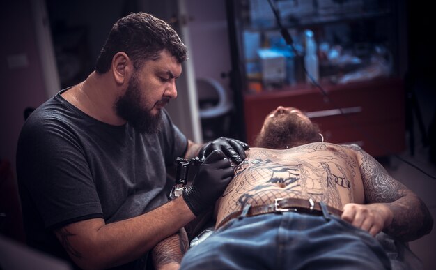 Un tatoueur professionnel montre le processus de tatouage de salon de tatouage.