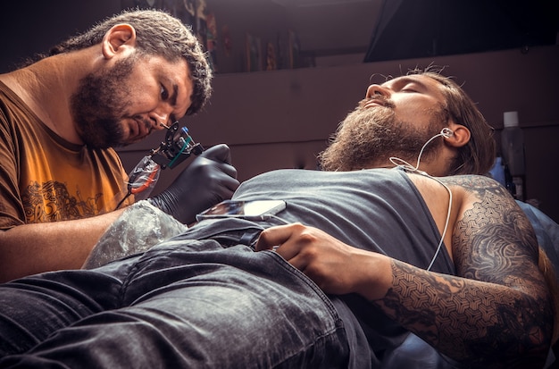 Tatoueur professionnel travaillant le tatouage dans un salon de tatouage