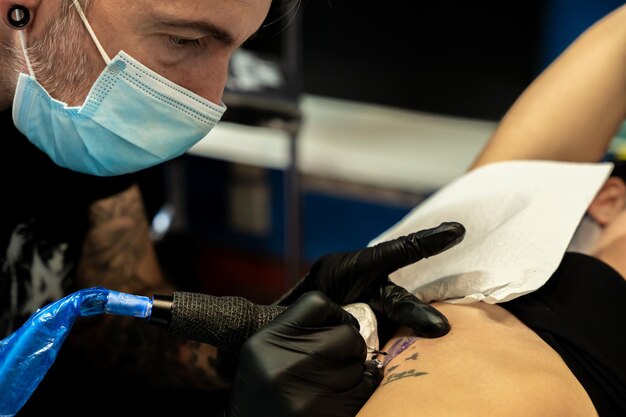 Tatoueur se concentrant tout en travaillant sur la peau d'une femme méconnaissable concept de travail et de concentration