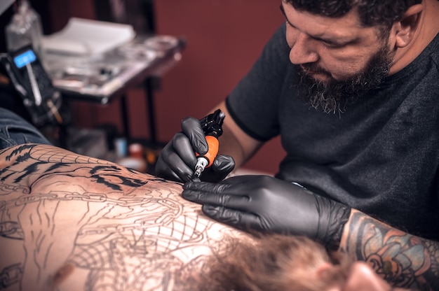 Tatoueur travaillant sur une mitrailleuse de tatouage professionnel dans un salon de tatouage.