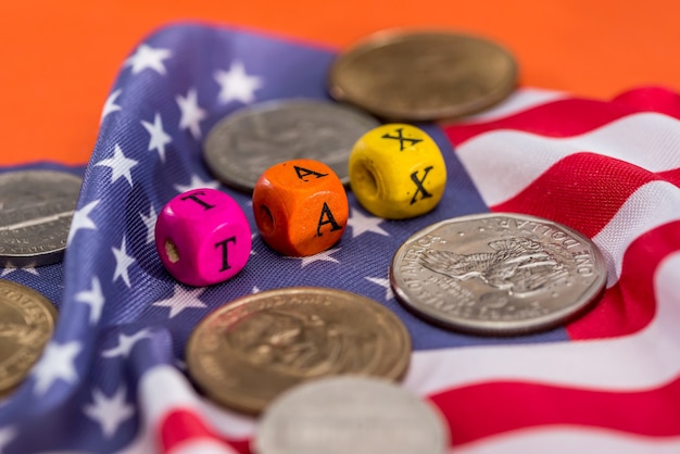 Taxe de cubes en bois avec drapeau, dollar, pièce de monnaie et calculatrice sur fond orange