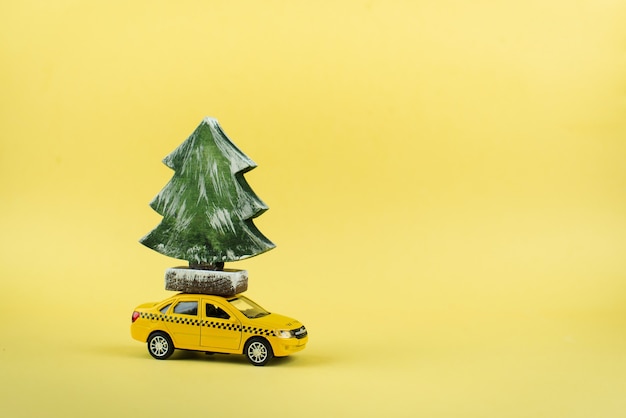 Taxi miniature jaune portant un arbre de Noël