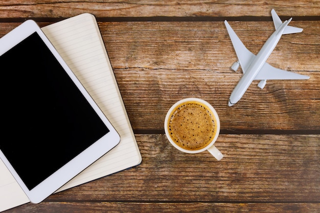 Été pour voyager concept sur fond de table en bois concept de voyage avec l'aide d'un modèle d'avion avion tablette numérique avec des notes de papier vierge, tasse de café