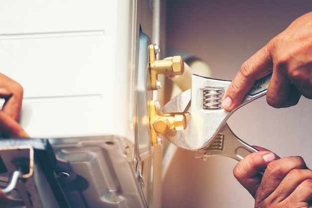 Technicien à l&#39;aide d&#39;une clé fixe pour serrer l&#39;unité extérieure de climatisation