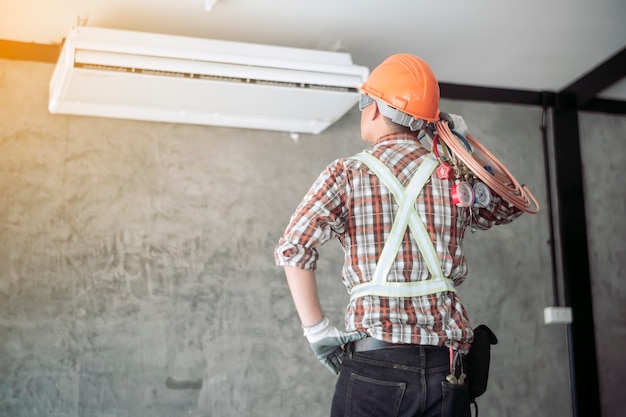 Technicien de l'air dans l'ensemble standard de sécurité Vérification de la qualité du climatiseur nouvellement installé.