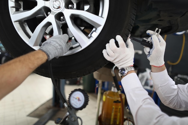 Le technicien automobile d'inspection de véhicule répare le pneu de voiture à la station-service