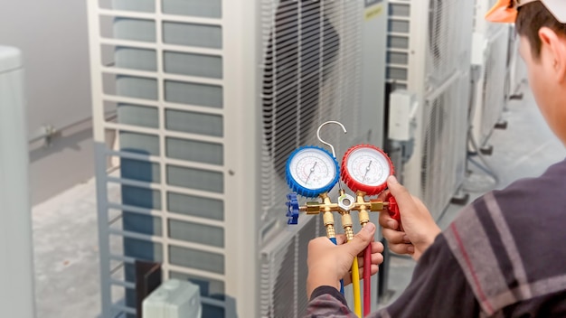 Technicien en climatisation réparant le système de climatisation central avec des outils extérieurs.