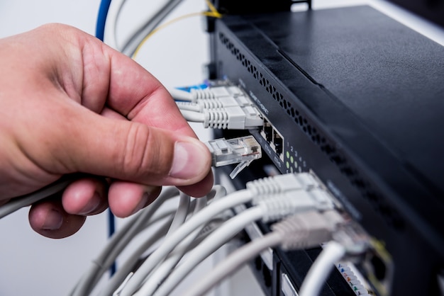 Technicien connectant les câbles réseau aux commutateurs. Connexion des câbles dans l'armoire du serveur.