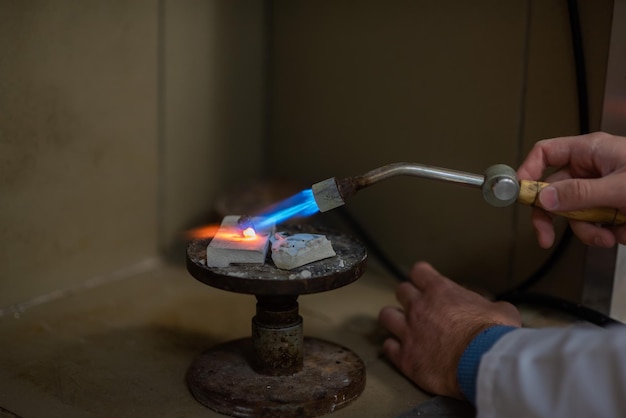 Un technicien dentaire fabrique des prothèses partielles La production d'une fausse mâchoire ou de ponts dentaires à l'aide d'un brûleur à gaz manuel Gros plan