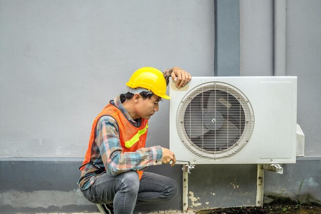 Le technicien du climatiseur utilise une clé pour serrer l'écrou du compresseur d'air