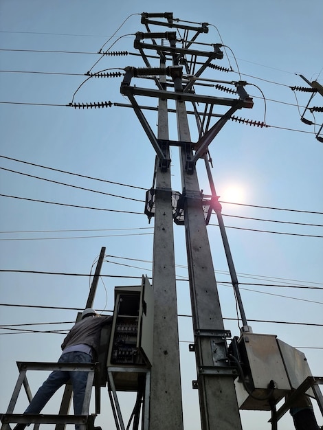 Technicien électricien opérant pour ouvrir l'interrupteur de coupure de charge 115kV sur ciel bleu avec fond de soleil