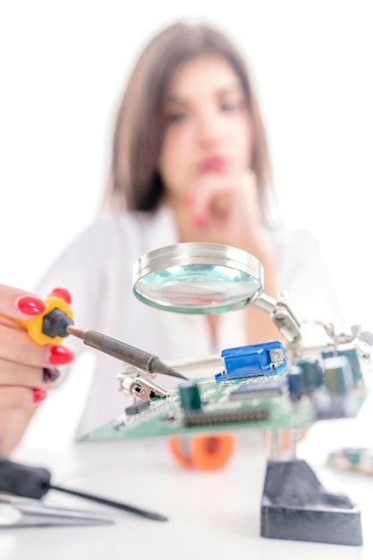 Technicien en électronique femme réparant l'équipement électronique à l'aide d'un fer à souder électrique