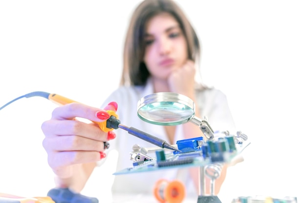 Technicien en électronique femme réparant l'équipement électronique à l'aide d'un fer à souder électrique