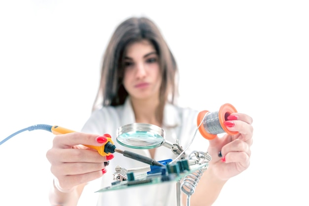 Technicien en électronique femme réparant l'équipement électronique à l'aide d'un fer à souder électrique