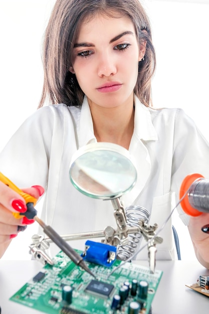 Technicien en électronique femme réparant l'équipement électronique à l'aide d'un fer à souder électrique