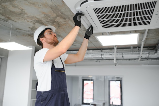 Un technicien heureux qui répare un climatiseur.