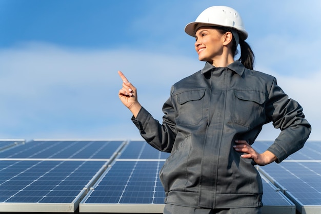 Technicien industriel féminin en uniforme près des batteries énergétiques à la campagne