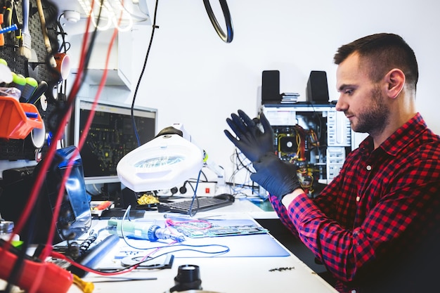 Technicien ingénieur informatique réparant un composant informatique dans un atelier de maintenance et d'entretien électronique