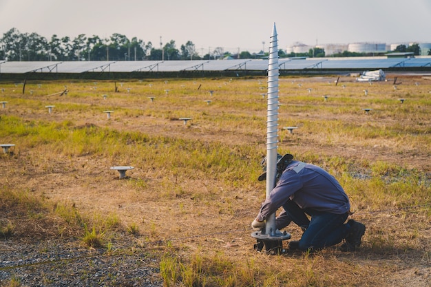 Technicien installant une vis de terre pour la structure de montage d'un panneau solaire dans une ferme solaire