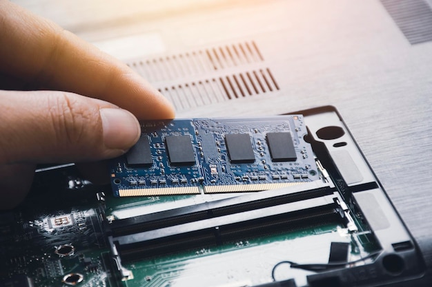 Technicien installer une nouvelle mémoire d'accès aléatoire RAM à l'emplacement de mémoire sur la carte mère de l'ordinateur portable