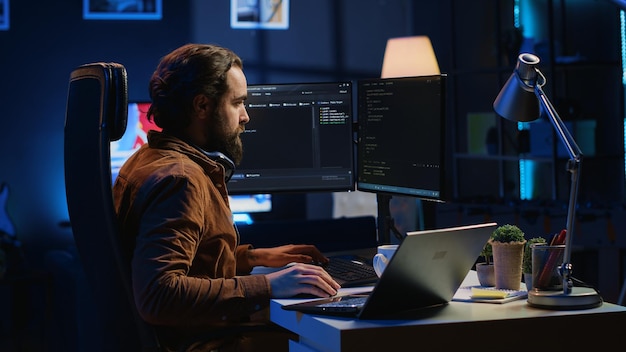 Technicien logiciel tapant du code dans un bureau personnel éclairé au néon