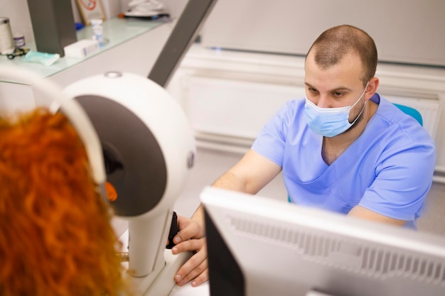 Technicien masculin avec un équipement d'exploitation de masque facial qui examine les yeux d'une cliente