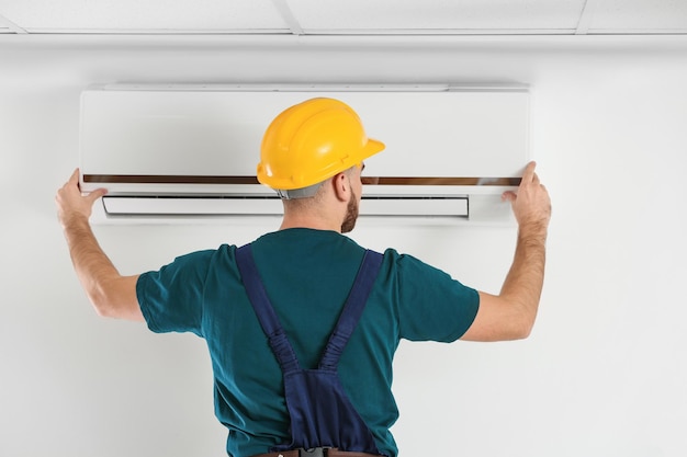 Technicien masculin fixant le climatiseur à l'intérieur