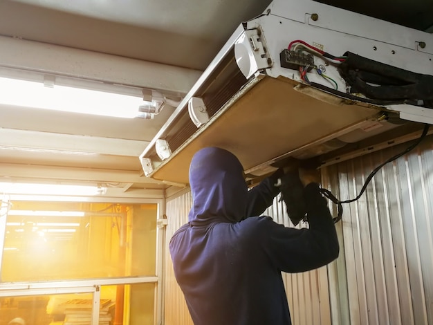 Technicien masculin vérifiant et réparant le climatiseur à l'intérieur, l'entretien et la réparation