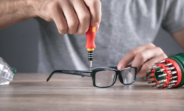 Technicien optique réparant des lunettes avec un tournevis.