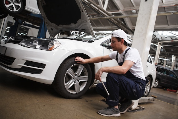 Technicien professionnel de service automobile examinant les roues d'une automobile