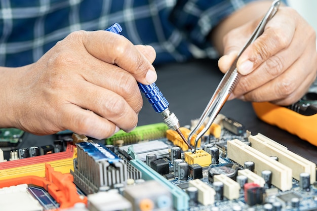 Photo technicien réparant à l'intérieur du téléphone mobile en fer à souder circuit intégré le concept de la technologie du matériel de données