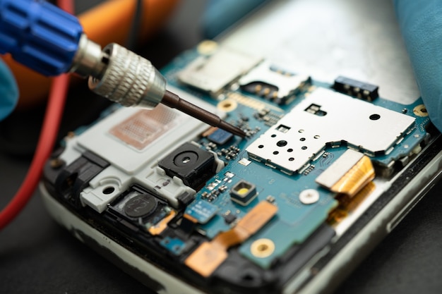 Technicien réparant l'intérieur du téléphone portable par fer à souder. Circuit intégré. le concept de données, de matériel, de technologie.