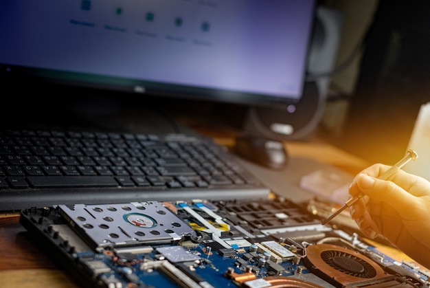 Technicien réparant un ordinateur portable cassé avec un tournevis